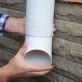Man installing plastic downspout system pipeline