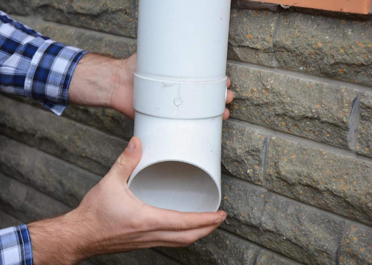 Man installing plastic downspout system pipeline