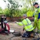 A sewer camera inspection is being conducted by two professionals.
